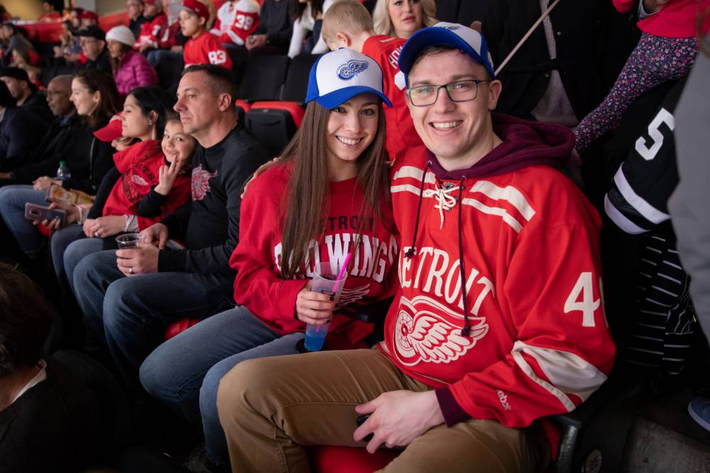 Two alumni smile for a photo while watching the game at the Detroit Red Wings GVSU Night